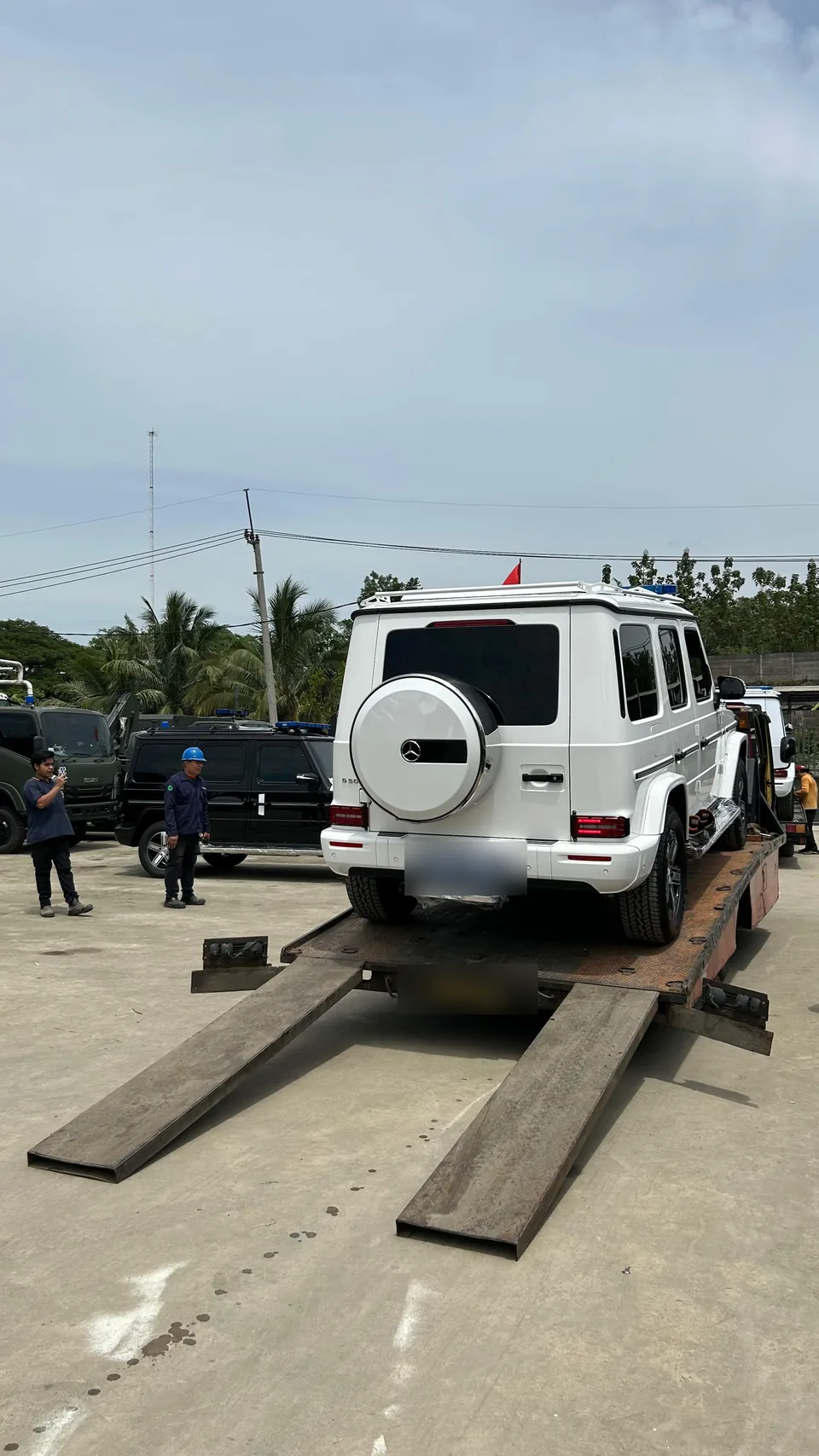 Kendaraan pada platform angkut dengan ramp di area terbuka.